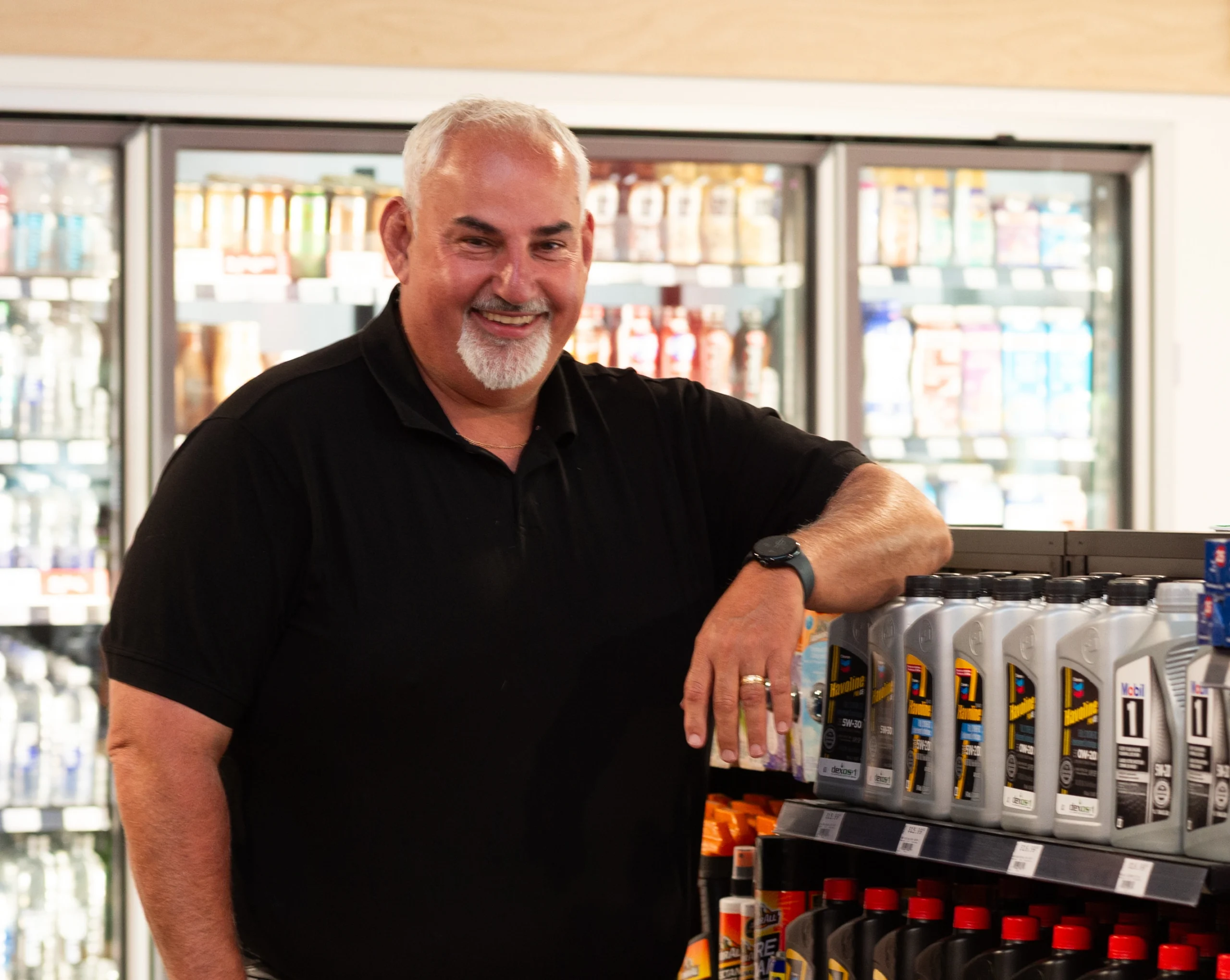 A smiling convenience store employee with arms crossed
