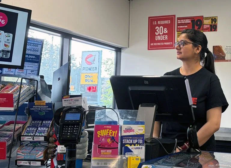 A store employee smiling behind the checkout counter