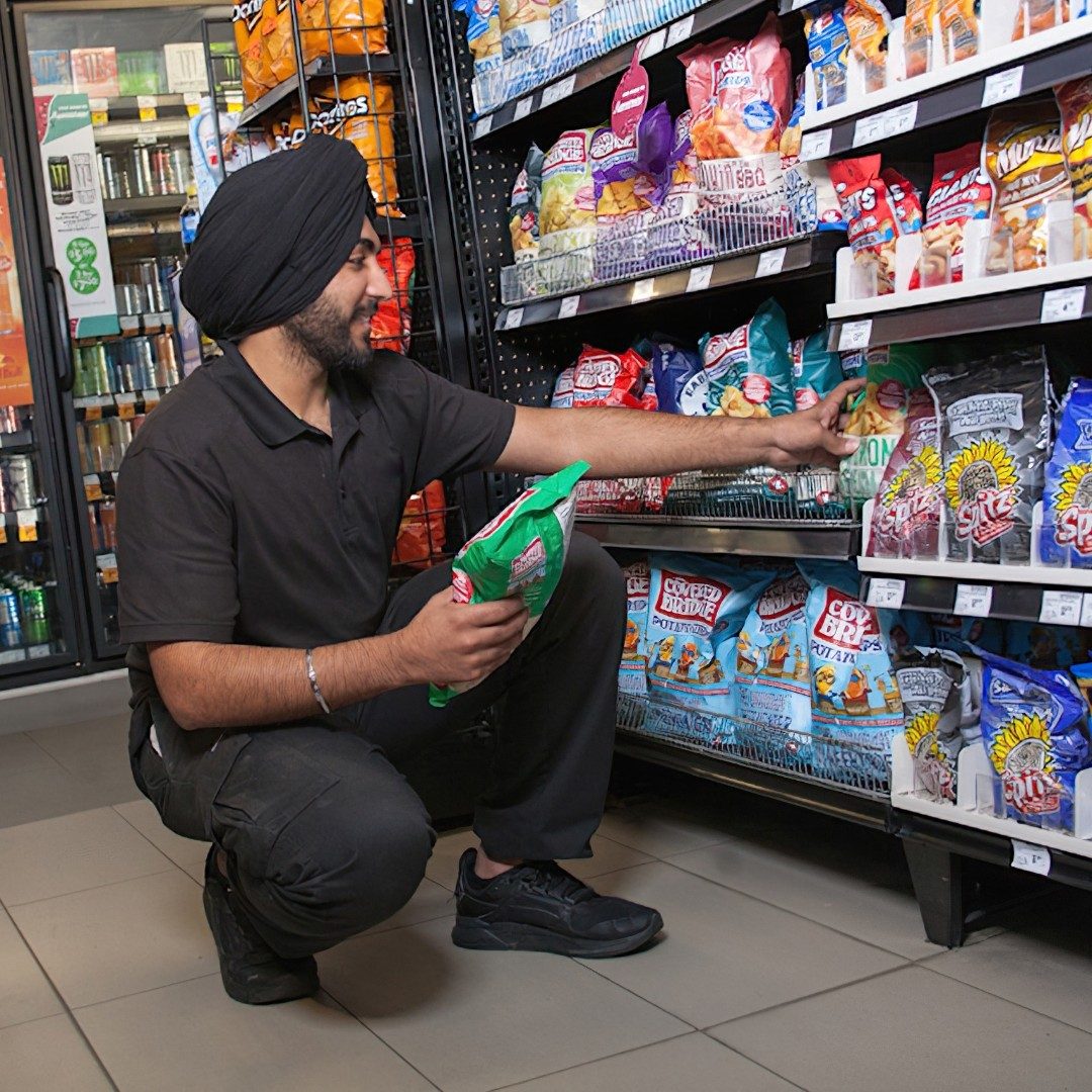 Un employé de dépanneur en train de réapprovisionner une tablette